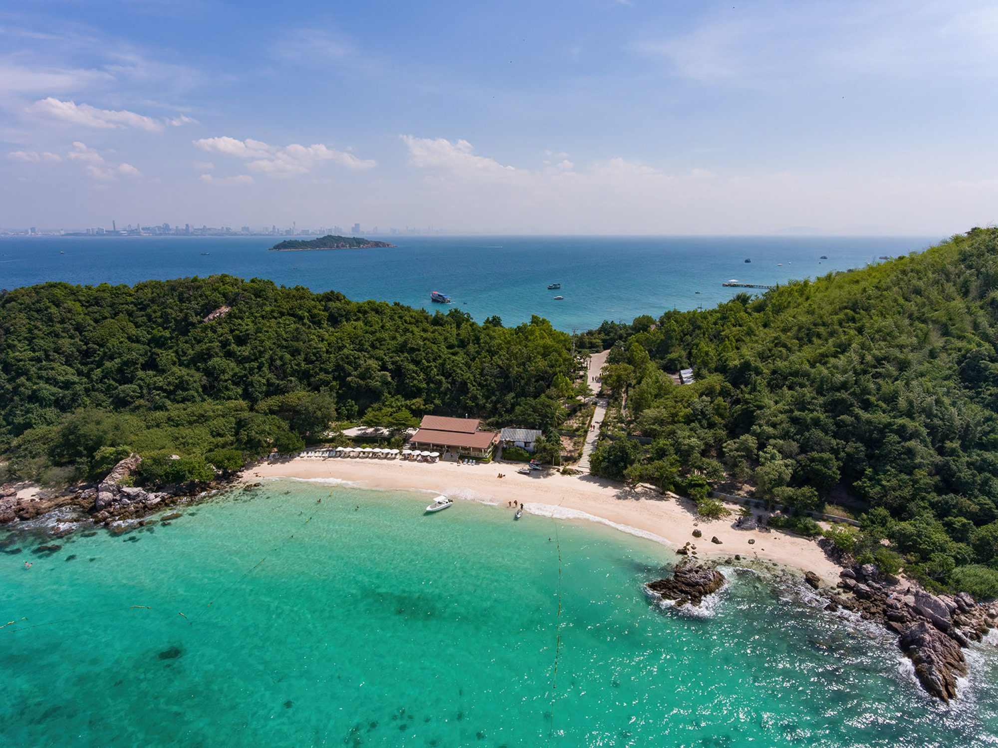 Scenic view of Ta Yai Beach with turquoise waters and lush tropical surroundings on Koh Larn Island.
